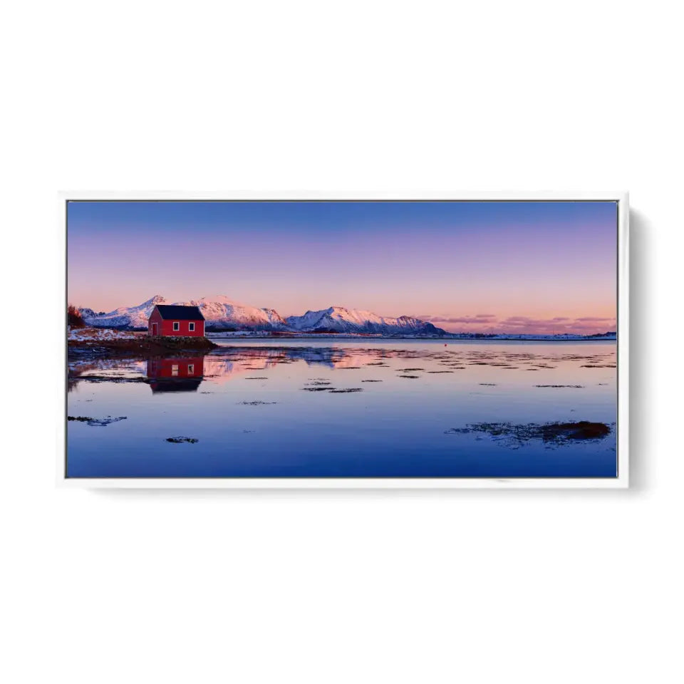 Beautiful winter lake, red rorbu house and snowy mountains at sunset