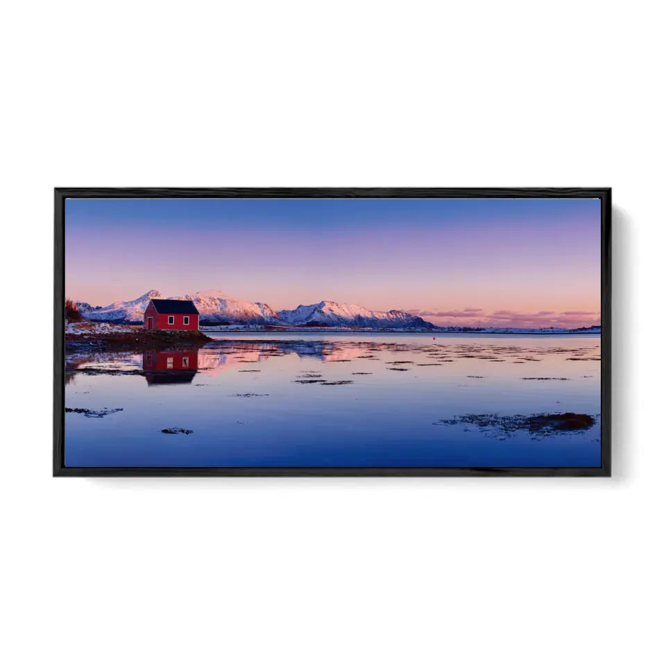 Beautiful winter lake, red rorbu house and snowy mountains at sunset