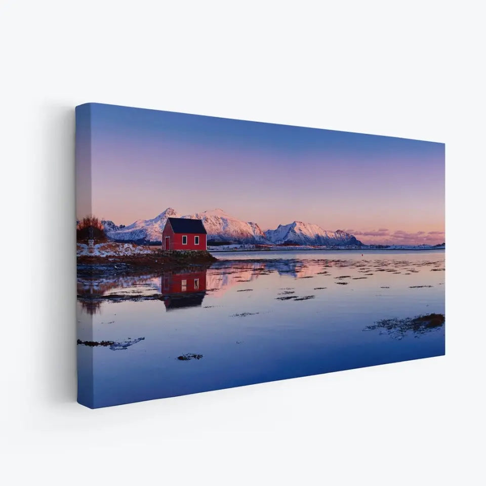 Beautiful winter lake, red rorbu house and snowy mountains at sunset