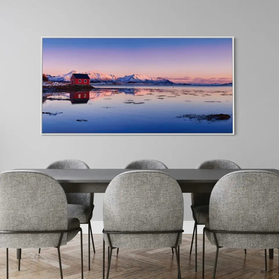 Beautiful winter lake, red rorbu house and snowy mountains at sunset